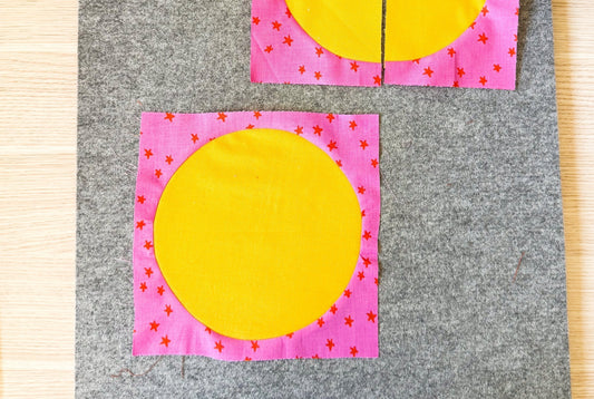 An inset circle is laying on a wool pressing mat. The centre of the circle is yellow and the outer fabric is pink starry. 